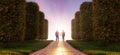 Path in a garden with green grass and bushes leading to a couple holding hands. Royalty Free Stock Photo