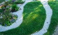 Path in a garden of pebbles and gravel, near the green grass lawn Royalty Free Stock Photo