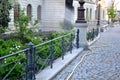 Path of granite cobblestones decorative black fence at the edge of flowerbed gardener let water yellow hose which spray water near Royalty Free Stock Photo