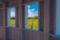 Path in the grass field through the wooden window view. Meadow picturesque summer landscape with clouds on blue marvelous sky