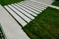 Path through the grassy meadow of the garden. tiles with stripes tile pattern. concrete white lawn diagonally. garden details with