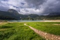 A path in a green meadow to a beautiful mountain lake. Beautiful mountain landscape Royalty Free Stock Photo