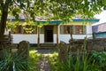 Path lead to a museum in old restored soviet house with open doors and windows ready to invite tourists, shade from a tree