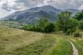 A path leading through a field toward forest and mountains. Royalty Free Stock Photo