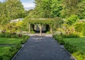 A path leading to a sundial in a bontanical garden, through hedges
