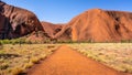 Path leading to the waterhole of the Kuniya walk with Ayers rock in background in outback Australia
