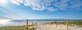 A path with many tracks, delimited by wooden posts on the sand dune with wild grass and beach in Noordwijk on the North Sea in Royalty Free Stock Photo