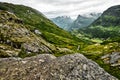 Path over green pasture in the mountains of Western Norway with snow on the summits and a dark cloudy sky Royalty Free Stock Photo