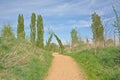 Path through a park along poplars with arch made of willow branches Royalty Free Stock Photo