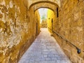 The path of pawing stones. Stone path to the archway in the tower of the ancient city. Alley in old town, late afternoon, late Royalty Free Stock Photo