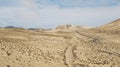 Path road in the middle of a mountains sand desert with blue bright sky in background. Concept of desertification or climate