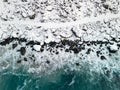 Path in the snow next to a wild shore with waves of blue ocean. Aerial view of dangerous winter pathway in Norway Royalty Free Stock Photo