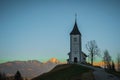 Path towards cute  fantastic charming Saint Primoz church on a small hill with mountains in background at sunset, Jamnik village, Royalty Free Stock Photo