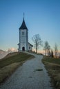 Path towards cute  fantastic charming Saint Primoz church on a small hill with mountains in background at sunset, Jamnik village, Royalty Free Stock Photo