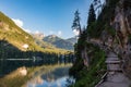 A path with a wooden fence climbs steeply beside the Braies lake