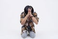 A pathetic and fearful young asian man bowing down and begging to be spared. Isolated on a white background
