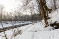 Paths running along the bank of the river flowing through the winter forest in front of the sunset Royalty Free Stock Photo