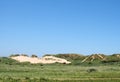 Paths through tall grass covered sand dune landscape in front of the sea and bright blue sea in summer sunshine Royalty Free Stock Photo