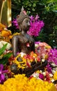 A bronze small Buddha statue at the temple with wet yellow red flower corollas for Songkran festival