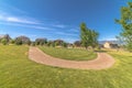 Pathway curving through vast grassy field with homes lake and mountain view Royalty Free Stock Photo