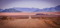 A pathway in a desert area surrounded by breathtaking mountains under the clear sky Royalty Free Stock Photo