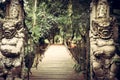 Pathway leading to tropical forest with terrible statues of Asian Buddhism demons on both sides in vintage style