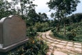 Pathway and an old memorial statue next to it in Angkor Botanical Garden, Cambodia Royalty Free Stock Photo