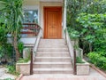 Pathway and stairs through the garden of a family house entrance with natural brown wood door. Royalty Free Stock Photo