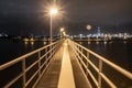 Pathway to the Night: Illuminated Pier Against City Lights Royalty Free Stock Photo