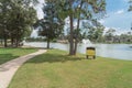 Pathway under tree lush at lakeside neighborhood park with duck house and mansion in Houston, Texas