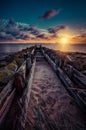 A pathway with wooden railings surrounded by huge rocks under the breathtaking sky during sunset Royalty Free Stock Photo