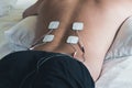 Patient applying electrical stimulation therapy on back. Electrical tens.