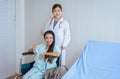 Patient woman is sitting in a wheelchair with doctor standing behind smiling and thumbs up Royalty Free Stock Photo