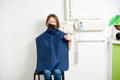 Patient of a dental office with a kofferdam is smiling to the camera while sitting on the chair in a white room