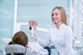 Dentist holding tooth shaped mirror for client. Royalty Free Stock Photo