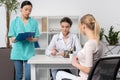 Patient with doctor and internist sitting at table during consultation in clinic