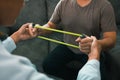 Patient doing stretching exercise with a flexible exercise band and a physical therapist hand to help in clinic room Royalty Free Stock Photo