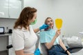 patient is enjoying her toothy smile looking in mirror in dental office held by the dentist. Royalty Free Stock Photo