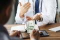 Patient giving money to medical doctor in hospital setting. Doctor gladly accepts a bribe from the patient actively Royalty Free Stock Photo