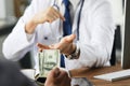 Patient giving money to medical doctor in hospital setting. Doctor gladly accepts a bribe from the patient actively Royalty Free Stock Photo