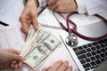 Patient giving money to medical doctor in hospital setting Royalty Free Stock Photo