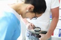 Patient holds magnifying glass over pants of medical worker smiling looks.