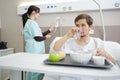 patient in hospital bed eating food from tray