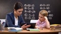 Patient lady teacher explaining subject on tablet, schoolboy does not understand