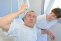 Patient lifting himself out bed with hoist nurse helping Royalty Free Stock Photo