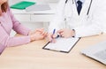 Patient listening intently to a male doctor explaining patient symptoms or asking a question as they discuss paperwork together in