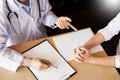 Patient listening intently to a male doctor explaining patient symptoms or asking a question as they discuss paperwork together in