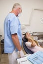 Patient lying in chair touching painful mouth looking at dentist