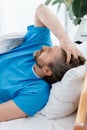 patient in medical gown lying and touching head in hospital.