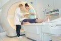 Patient on mri machine while two female doctors operating it